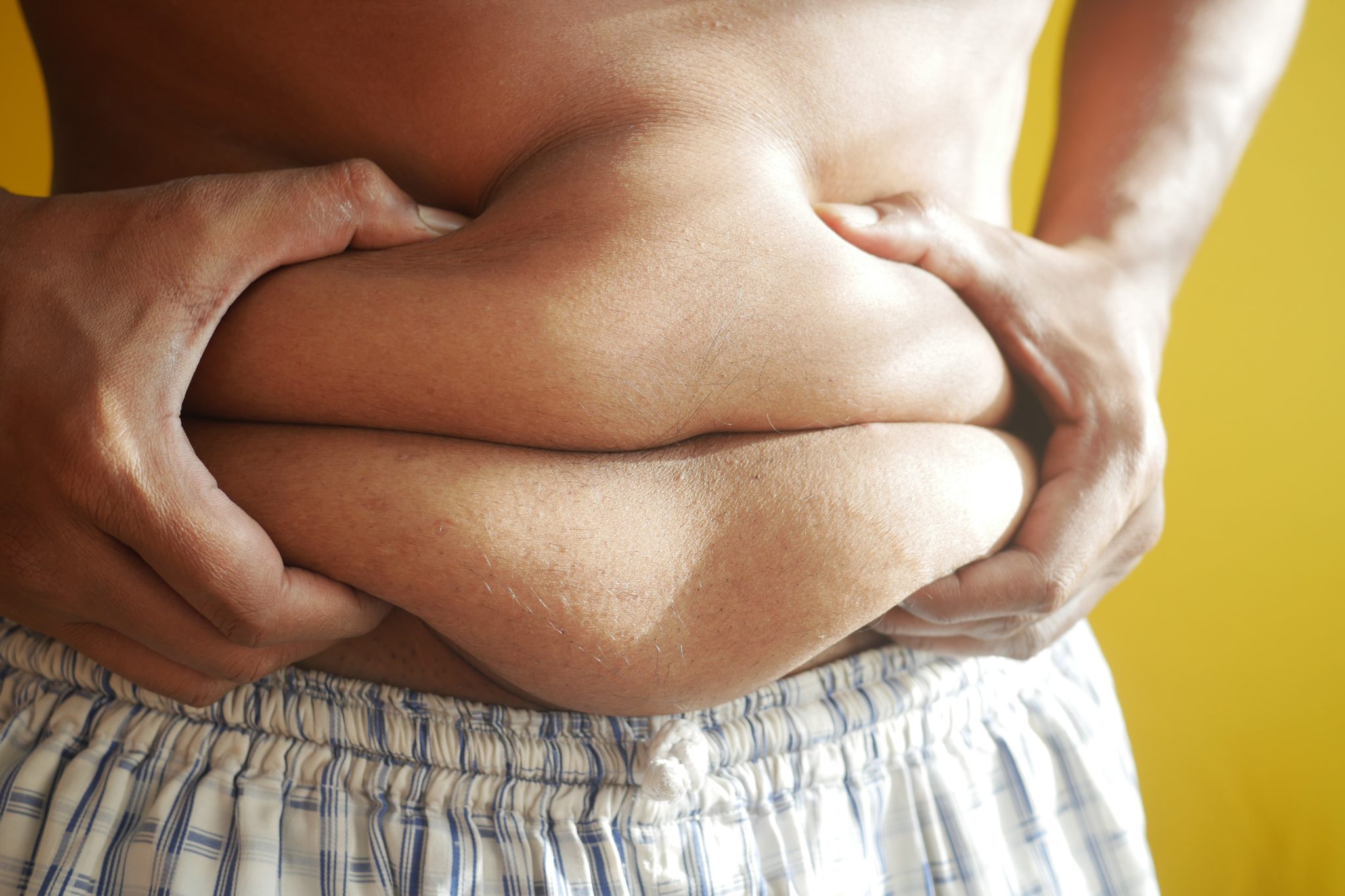 an overweight man grabbing his belly fat